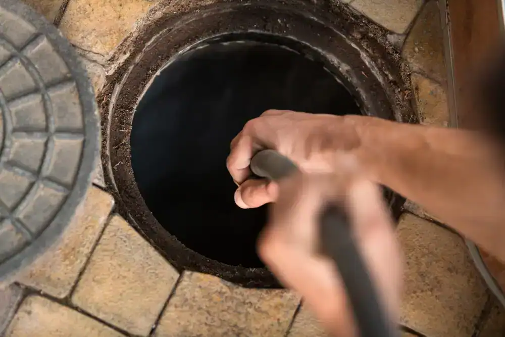 Technician cleaning a sewer manhole in Cook County, Illinois using professional hydro jetting equipment for All Rooter Hydro Jetting Experts